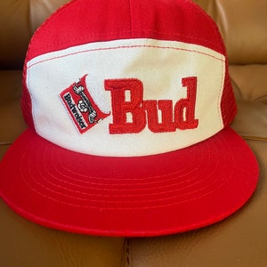 Puede incluir: Gorra de camionero roja y blanca con un logotipo de Budweiser y la palabra "Bud" bordada en rojo en la parte delantera.