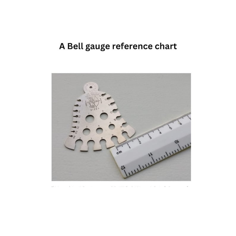 May include: A silver bell-shaped gauge with numbered holes for measuring different sizes. The gauge is next to a ruler marked in centimeters.