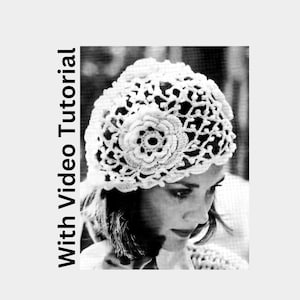 Puede incluir: Un gorro blanco de ganchillo con un diseño floral. El gorro está hecho con puntadas delicadas y tiene un aspecto de encaje.