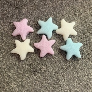 May include: Six starfish-shaped bath soaps in pastel colors. The soaps are light blue, pink, and white.