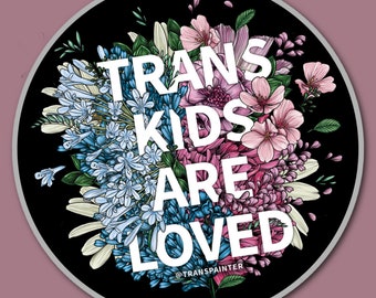 May include: A black and white circular sticker with a floral design. The flowers are pink, blue, and white. The text "TRANS KIDS ARE LOVED" is written in white letters on the sticker. The text "@TRANSPAINTER" is written in white letters at the bottom of the sticker.