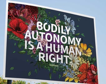 May include: A sign with the text "BODILY AUTONOMY IS A HUMAN RIGHT" in white, surrounded by a floral arrangement of red, purple, yellow, and white flowers against a dark blue background.