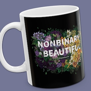 Puede incluir: Una taza negra con asa blanca y un diseño floral. El texto "Nonbinary is Beautiful" está impreso en blanco en la taza. El texto "@Transpainter" está impreso en blanco en la parte inferior de la taza.