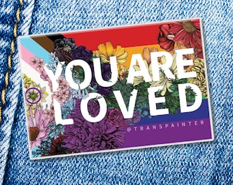Peut inclure: Un autocollant rectangulaire avec un fond de drapeau arc-en-ciel aux rayures horizontales marron, noir, bleu clair, rose, blanc, rouge, orange, jaune, vert et violet. Le texte YOU ARE LOVED est imprimé en blanc sur des illustrations florales.