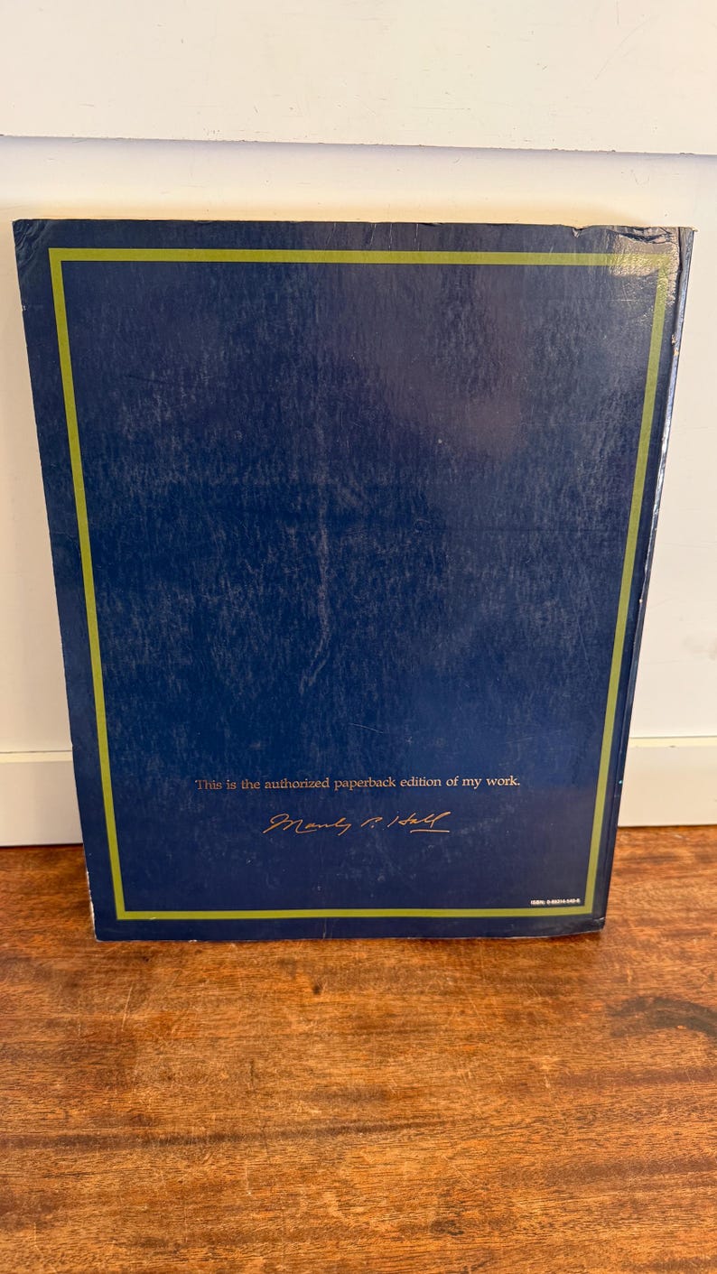 Może przedstawiać: Ciemnoniebieska książka w miękkiej oprawie ze złotą obw&oacute;dką. Na okładce znajduje się napis "This is the authorized paperback edition of my work" oraz podpis. Dzieło literackie.
