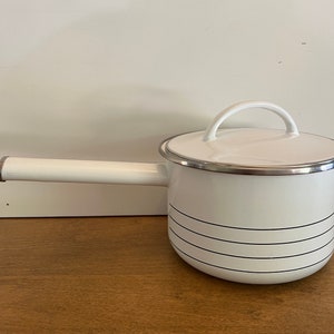 May include: White enamel saucepan with a black striped design and a silver lid. The saucepan has a silver handle.