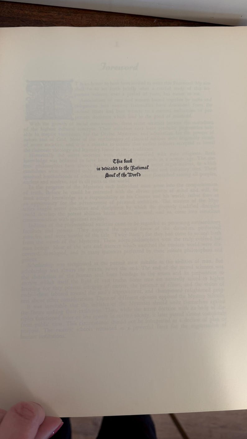Może przedstawiać: Otwarta strona książki z tekstem. Tekst brzmi &bdquo;Ta książka jest dedykowana Racjonalnej Duszy Świata&rdquo; w ozdobnej czcionce. Strona jest w kolorze złamanej bieli z delikatnym, teksturowanym wyglądem.