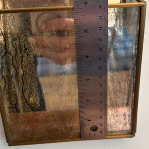 May include: A rectangular, vintage-style hanging planter with a tarnished brass frame and mirrored glass. The planter is approximately 6 inches tall. A brass chain is attached for hanging. The glass has a distressed, antique appearance.