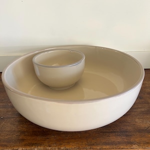 May include: A beige ceramic serving bowl with a smaller beige bowl inside. The larger bowl has a slightly darker rim.