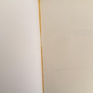 Może przedstawiać: Otwarta książka z postarzanymi, kremowymi stronami. Krawędź oprawy ma złoty brązowy kolor. Strony są puste, z bladym tekstem widocznym na prawej stronie. Książka jest otwarta, ukazując wewnętrzne strony.