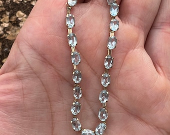 May include: A gold bracelet with oval-shaped light blue gemstones.