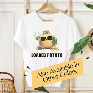 May include: White t-shirt with a cartoon potato wearing sunglasses and holding money. The text "LOADED POTATO" is printed below the image. The text "Also Available in Other Colors" is printed on a yellow banner.