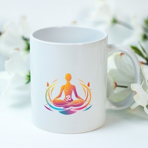 May include: White ceramic mug with a colorful illustration of a person in a yoga pose with the Om symbol in the center. The illustration is surrounded by a swirling design.