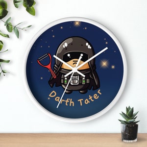 May include: A white round clock with a blue background and stars. A cartoon character resembling Darth Vader is holding a red potato peeler. The text "Darth Tater" is written below the character.