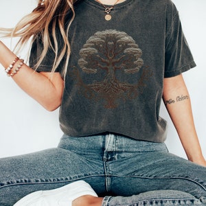 May include: A dark gray t-shirt with a brown tree of life design. The shirt has a relaxed fit and is made of a soft, comfortable fabric.
