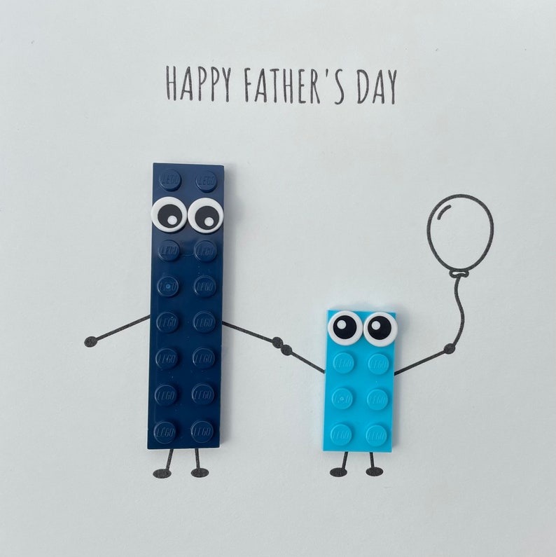 May include: Happy Father's Day card with two Lego figures. The taller figure is blue and has a balloon. The shorter figure is light blue and has a smile.