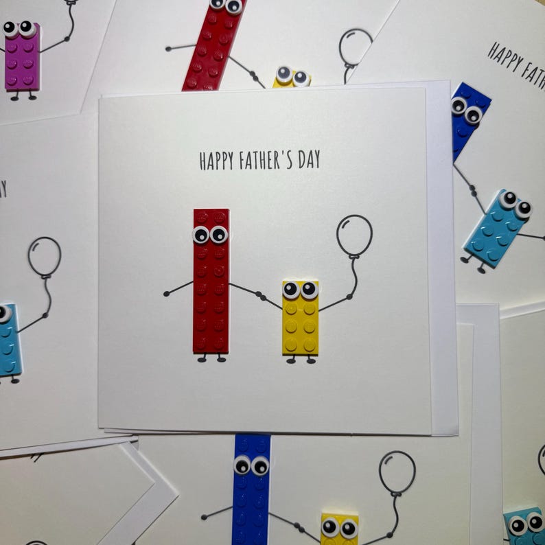 May include: A handmade card with a Happy Father's Day message. The card features two Lego-like figures, one red and one yellow, holding hands. The red figure is holding a balloon.