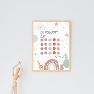 May include: A motivational chart with a white background and a wooden frame. The chart features a colorful illustration of a rainbow, a giraffe, a cactus, and a bear. The chart also includes a grid of 20 circles, with the text "DU SCHAFFST DAS!" and "SUPER!" at the top and bottom of the grid.