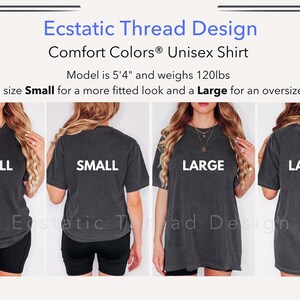 以下が含まれることがあります： 2人のモデルが同じユニセックスTシャツを異なるサイズで着用しています。左側のモデルはSサイズ、右側のモデルはLサイズを着用しています。Tシャツは濃いグレーで、背面に「SMALL」と「LARGE」の文字が印刷されています。