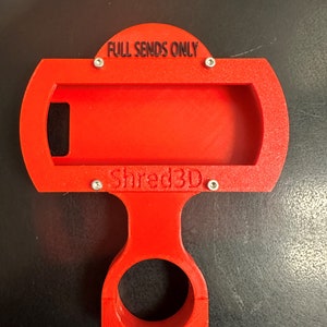 Peut inclure: Support de t&eacute;l&eacute;phone rouge imprim&eacute; en 3D avec une base circulaire et un support de t&eacute;l&eacute;phone rectangulaire. Le support porte l'inscription "FULL SENDS ONLY" et "Shred3D".