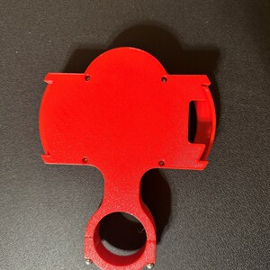 Peut inclure: Un support de t&eacute;l&eacute;phone en plastique rouge vif avec une pince pour le fixer &agrave; un guidon. Le support a une fente pour un t&eacute;l&eacute;phone et une ouverture circulaire pour un c&acirc;ble de charge.