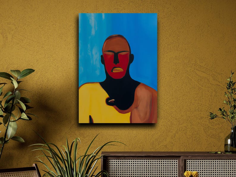 May include: Abstract portrait painting on canvas. The artwork features a figure with a red face, brown hair, and a yellow shirt against a blue background. The painting is mounted on a mustard-colored wall.