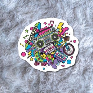 May include: A colorful sticker featuring a boombox, skateboard, roller skate, bicycle, and cassette tapes. The design includes musical notes, stars, and lightning bolts, with a retro 80s or 90s theme.