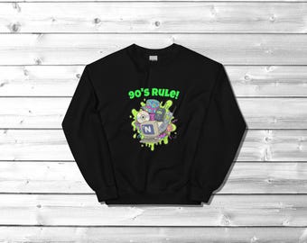 May include: Black sweatshirt with a colorful 90's graphic. The design includes a computer, CD, cell phone, and the text "90's RULE!" in neon green. The graphic is surrounded by a green, drippy design.