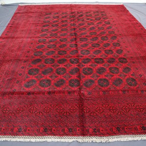 May include: A red and black patterned rug with a geometric design. The rug has a fringe border.