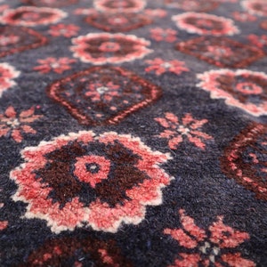 May include: Close-up of a blue rug with a repeating pattern of pink and brown floral designs.