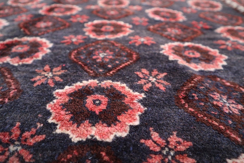 May include: Close-up of a blue rug with a repeating pattern of pink and brown floral designs.