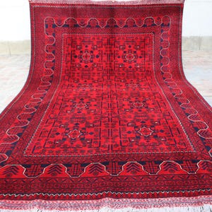May include: A red rug with a traditional Persian design. The rug has a dark blue border and a central medallion with intricate floral patterns.