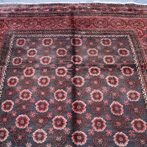 May include: A vintage Persian rug with a dark blue background and a repeating pattern of red and white flowers. The rug has a red border with intricate designs.