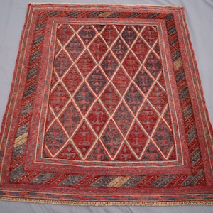 May include: A red, blue, and cream colored rug with a geometric diamond pattern. The rug has a fringe border.