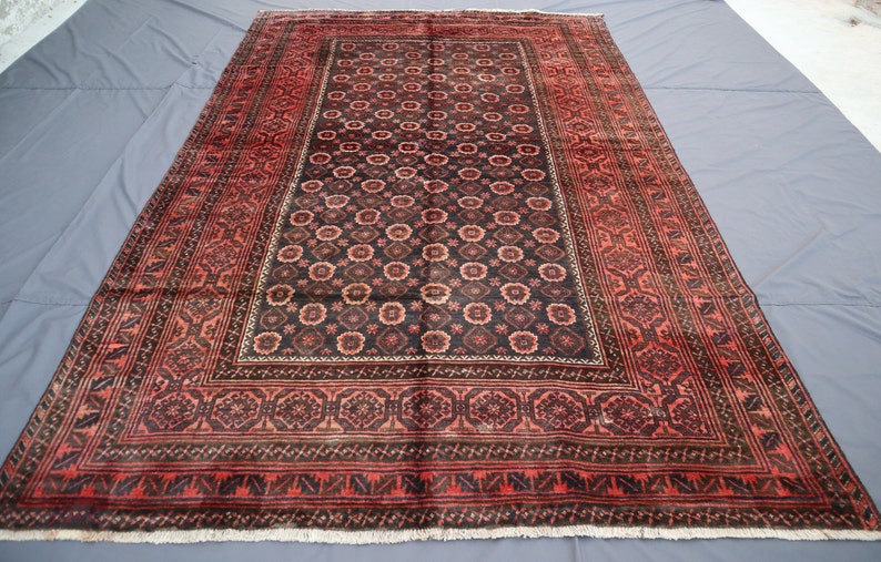 May include: A traditional Persian rug with a dark red and black color scheme. The rug features a central medallion with intricate floral patterns and a border with geometric designs.