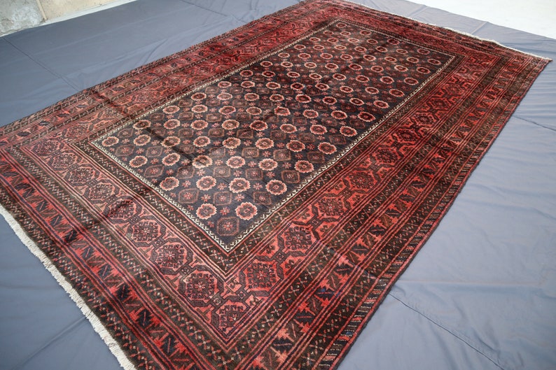 May include: A traditional Persian rug with a dark red and black color scheme. The rug features a central medallion with intricate floral patterns and a border with geometric designs.