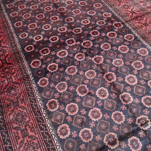May include: A traditional Persian rug with a dark blue background and a repeating pattern of red and white floral motifs. The rug has a border with a more intricate design.