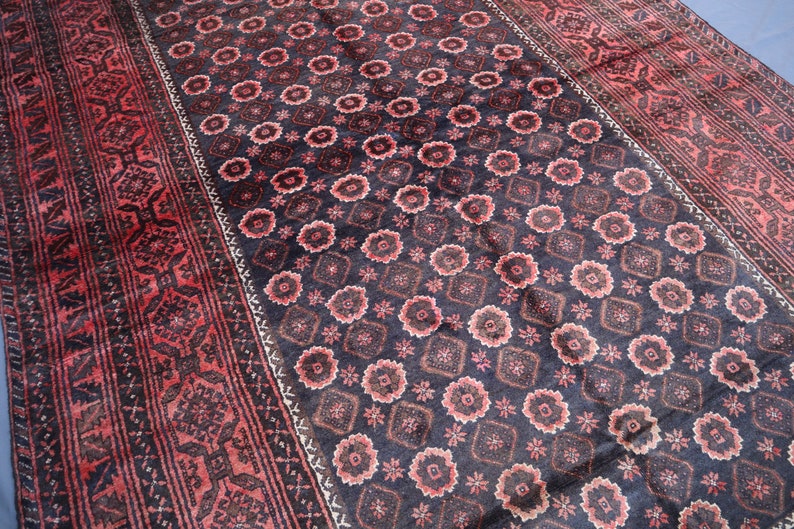 May include: A traditional Persian rug with a dark blue background and a repeating pattern of red and white floral motifs. The rug has a border with a more intricate design.
