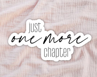 May include: A white sticker with black text that reads "just one more chapter" on a pink fabric background.