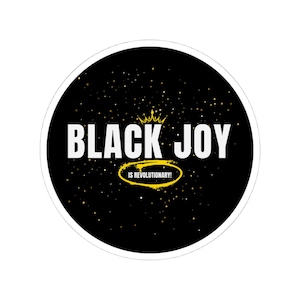 May include: Black and gold sticker with the text "Black Joy is Revolutionary!" on a black background with gold glitter.