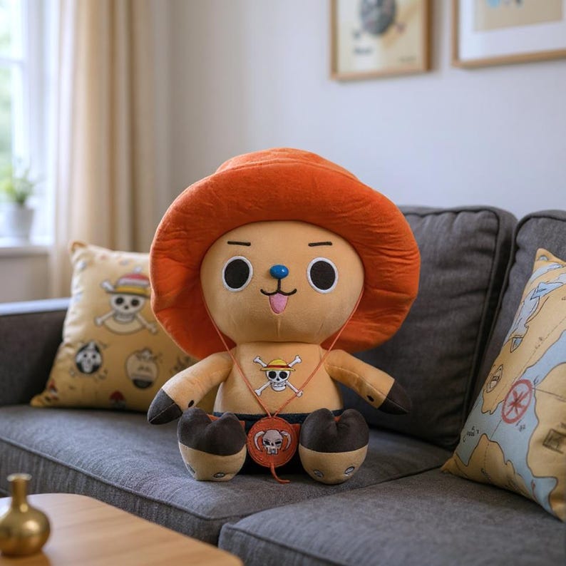 May include: A plush toy of a cartoon character with an orange hat and a skull and crossbones necklace. The toy is tan with black accents and is sitting on a gray couch. A pillow with a skull and crossbones design is visible.