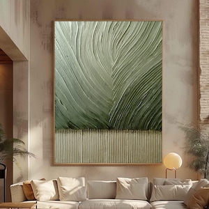 以下が含まれることがあります： テクスチャ加工された表面を持つ、大きな額入りの抽象芸術作品。このアートワークは、緑色のグラデーションと、テクスチャ加工されたベージュの水平バンドの上に葉のようなデザインが特徴です。このアートワークは、クリーム色のセクショナルソファの上に展示されています。