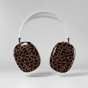 May include: White over-ear headphones with earcups featuring a brown and black leopard print design. The headphones have a white headband and black accents. The design is a modern take on a classic animal print.