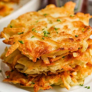 May include: A white ceramic mug with a black handle and the text "But First, Coffee" in a bold, black font. The mug is set against a blurred background, suggesting a cosy setting.