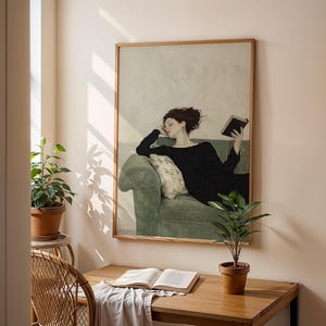 K&ouml;nnte beinhalten: Ein gerahmtes Gem&auml;lde einer Frau in einem schwarzen Kleid, die sich auf einem gr&uuml;nen Sofa zur&uuml;cklehnt und ein Buch liest. Das Gem&auml;lde ist vor einer hellbeigen Wand platziert, die von nat&uuml;rlichem Licht aus einem Fenster beleuchtet wird.