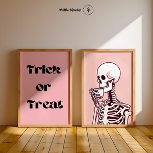 Puede incluir: Dos impresiones enmarcadas de color rosa con fondos blancos. La impresi&oacute;n de la izquierda tiene el texto "Trick or Treat" en negro. La impresi&oacute;n de la derecha presenta un esqueleto de dibujos animados sosteniendo una taza de caf&eacute;.