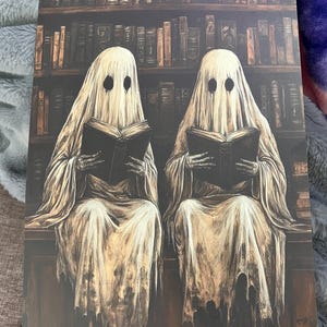 May include: Two white ghostly figures sit in front of a bookshelf filled with books, each holding a book in their hands. The ghosts have black eyes and are wearing white robes.