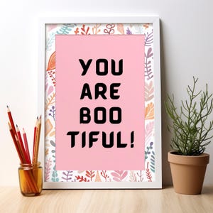 Puede incluir: Impresi&oacute;n enmarcada en blanco con fondo rosa y borde floral. El texto "YOU ARE BOOTIFUL!" est&aacute; impreso en negro.
