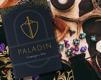 May include: A dark blue notebook with a gold shield and sword design. The notebook says "PALADIN Campaign Notes". The notebook is surrounded by dice, a leather pouch, and a wooden antler.