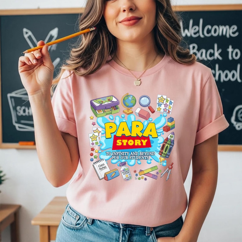 K&ouml;nnte beinhalten: Hellrosa T-Shirt mit dem farbenfrohen Schriftzug "PARA STORY". Das Design zeigt schulische Illustrationen wie einen Globus, einen Radiergummi und eine Rakete. Der Text "TO INFINITY AND BEYOND FOR OUR STUDENTS" ist ebenfalls enthalten.